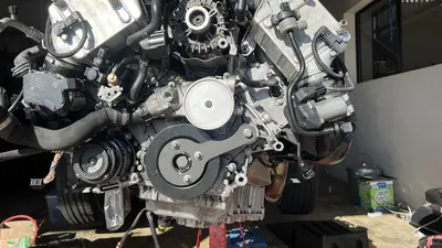 ล็อก harmonic balancer ด้วยเครื่องมือจับ — น็อต 27 มม. ขันที่ 100 Nm แล้ว +60° สามครั้ง (ยืดรวม 180°)